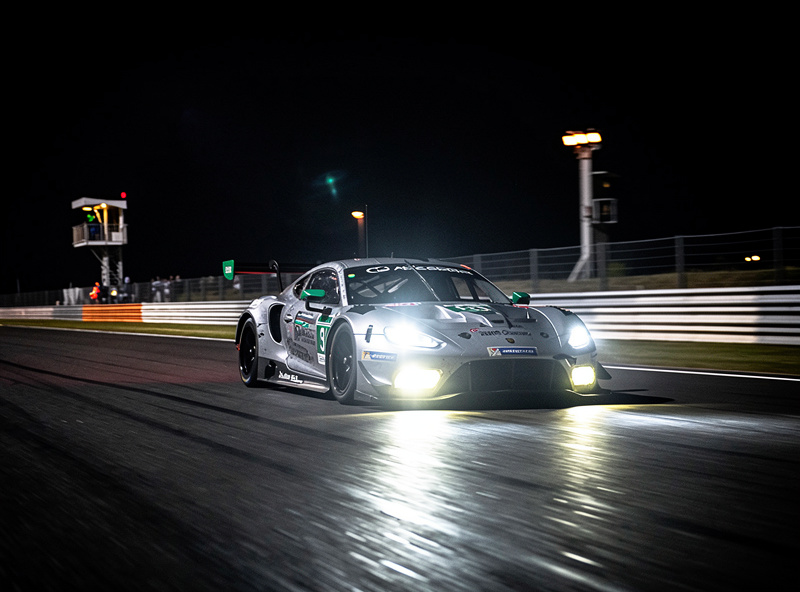 GT3 car racing at night with headlights illuminating the track ahead in ACC
