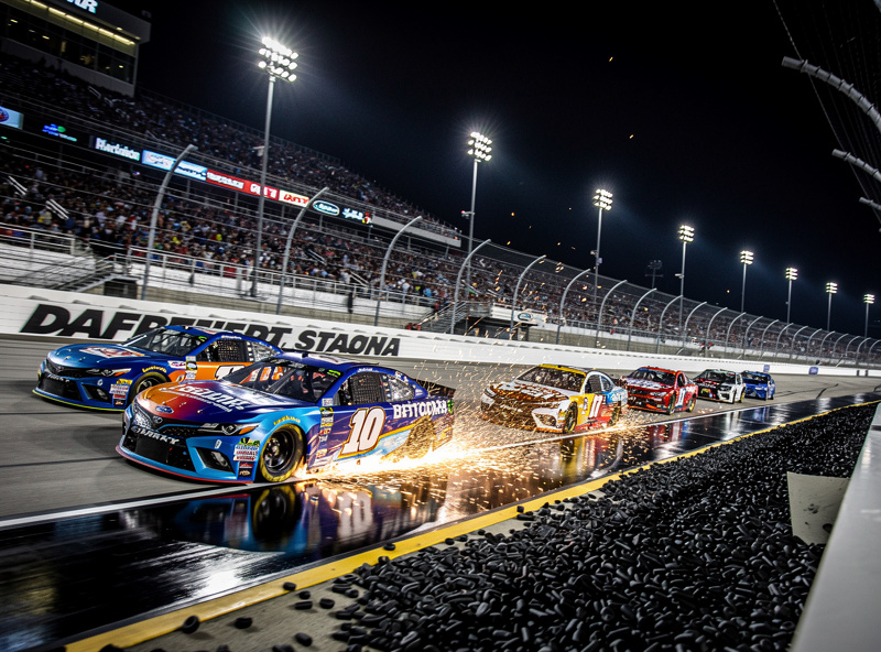 Daytona International Speedway at night with NASCAR stock cars racing under lights