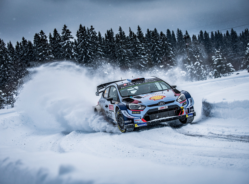 Rally car on snowy winter stage with snow spraying from tires