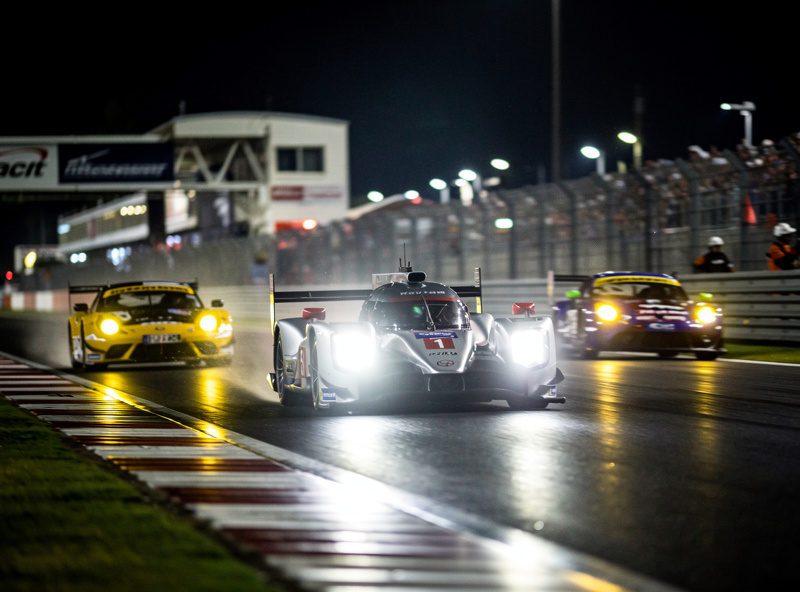 Prototype car overtaking GT cars in multi-class racing at night