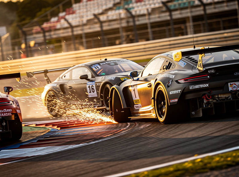 GT3 race cars battling through a corner with sparks visible