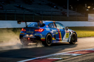 Rear-drive race car powering out of a corner under throttle