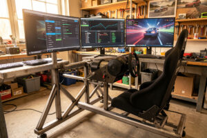 Sim racing cockpit with a direct-drive wheelbase and force feedback tuning menu on a triple-monitor setup