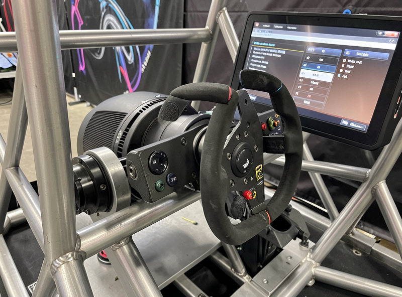 Direct-drive sim racing wheelbase mounted on a welded steel cockpit with a force feedback tuning menu on screen