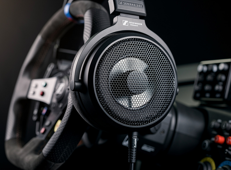 Close-up of open-back headphones with angled drivers on sim racing wheel