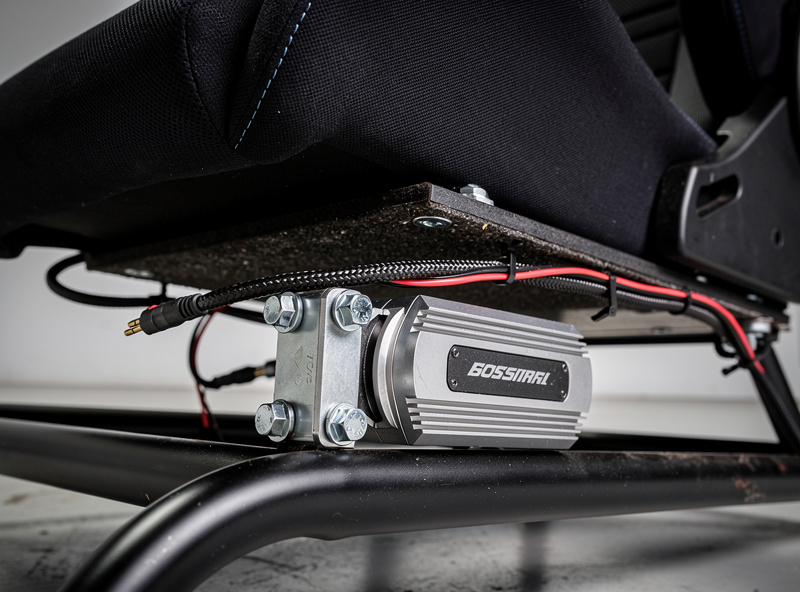 Tactile transducer bolted under a sim racing seat on a steel-tube cockpit
