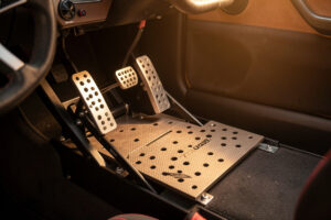 Load-cell sim racing pedal set on a braced pedal plate with a heel rest