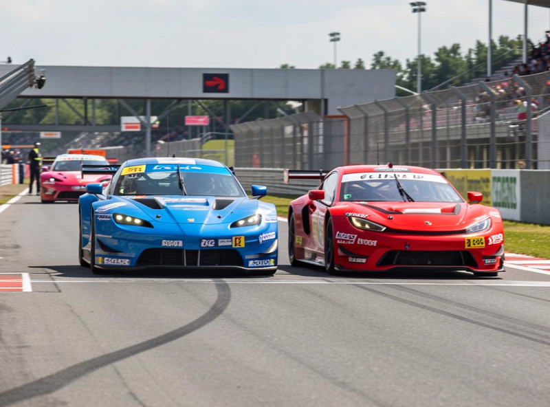 Two GT cars exiting the pit lane during an endurance race undercut battle