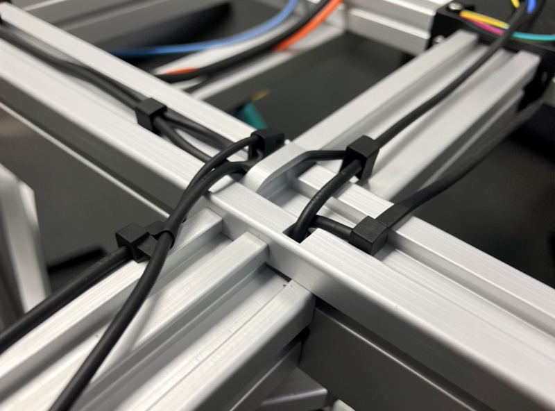Cables routed and clipped along the T-slot channels of an aluminum profile sim racing rig