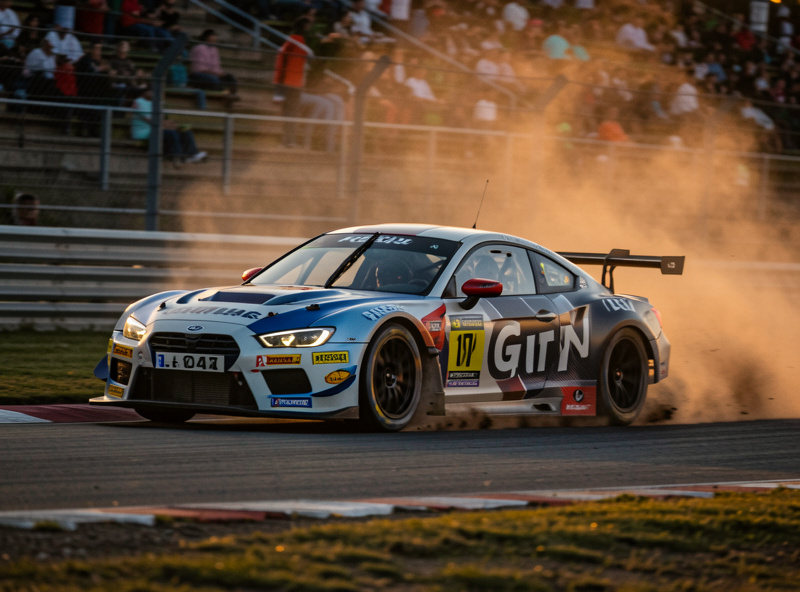 A GT race car late in a stint sliding slightly through a corner on worn tyres
