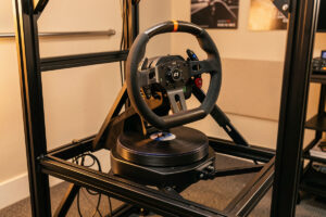 Direct-drive sim racing wheelbase mounted on a braced wheel deck with a GT-style rim