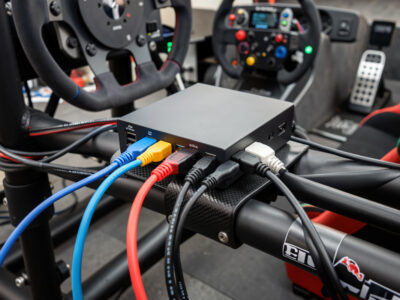 Powered USB hub mounted on a sim racing rig with peripheral cables plugged in