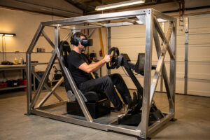 VR sim racing cockpit with headset, direct-drive wheel and load-cell pedals on a welded steel rig