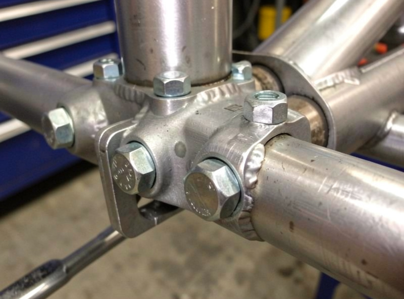 Close-up of a bolted lap joint between two steel tubes with hex bolts and a bracket