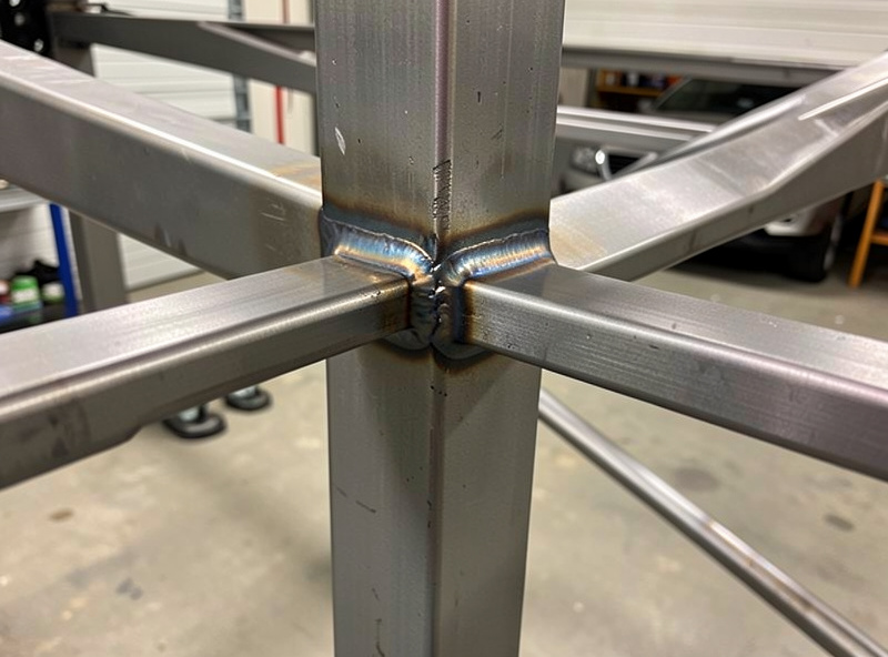 A welded steel T-joint on a sim rig frame ground smooth with a clean weld bead