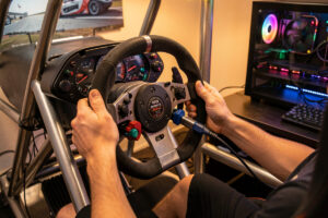 Sim racing wheelbase being unplugged from a console and plugged into a gaming PC mid-swap