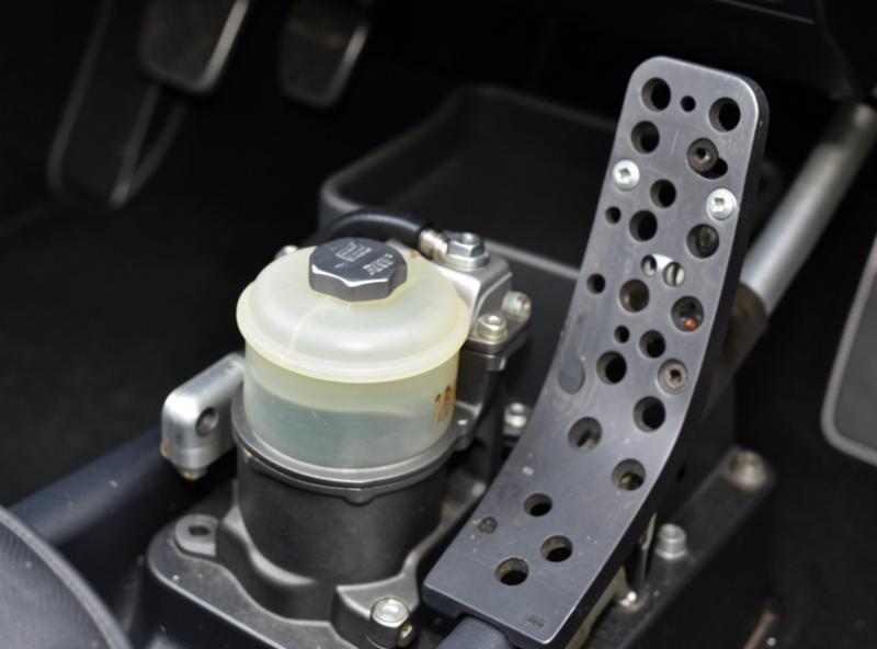 Close-up of a hydraulic sim racing brake pedal showing the master cylinder and reservoir
