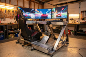 DIY welded steel sim-racing cockpit with a load-cell pedal set and triple monitors