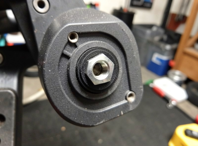 Close-up of a load-cell sim-racing brake pedal showing the elastomer stack and preload nut behind the pedal face