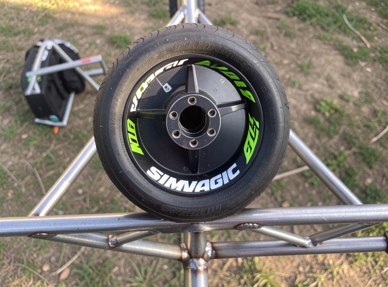 A Simagic Alpha direct-drive base and formula rim mounted on a welded sim rig