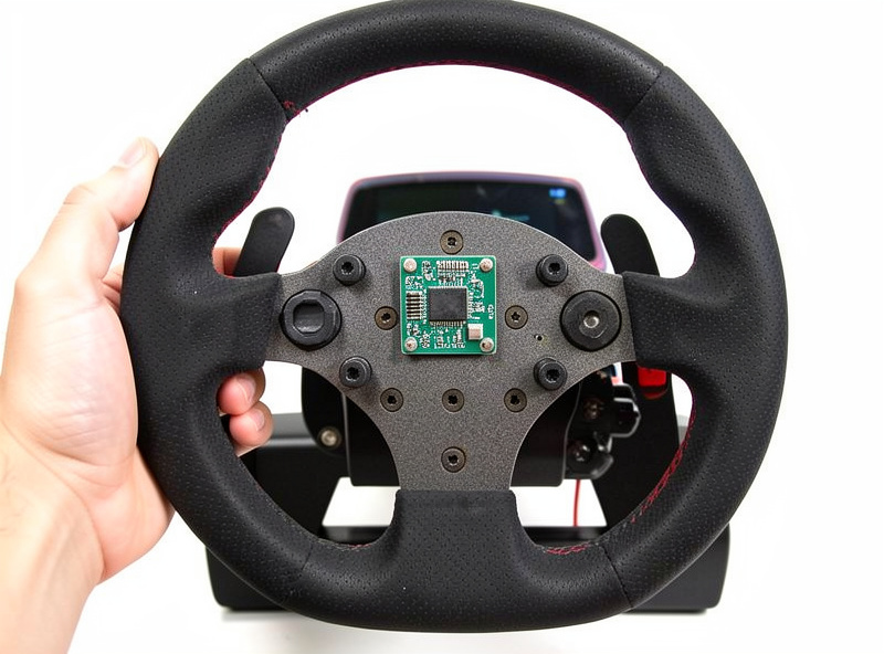 Hand holding a sim racing wheel rim with a licensing chip circuit board visible